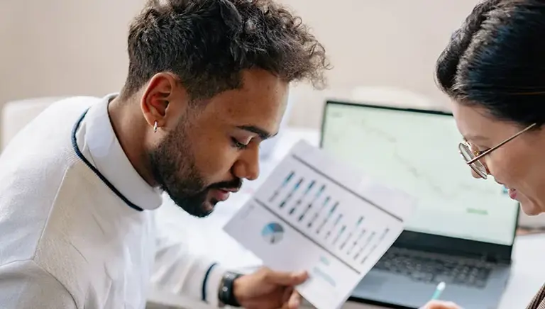 Two office workers chat over a laptop