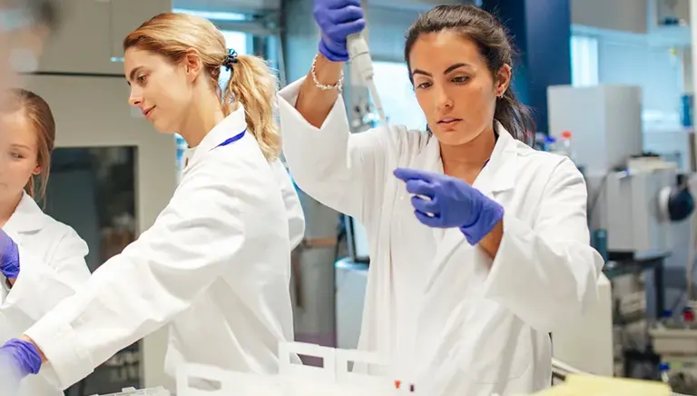 Three young scientists are seen working on a number of vials in the lab