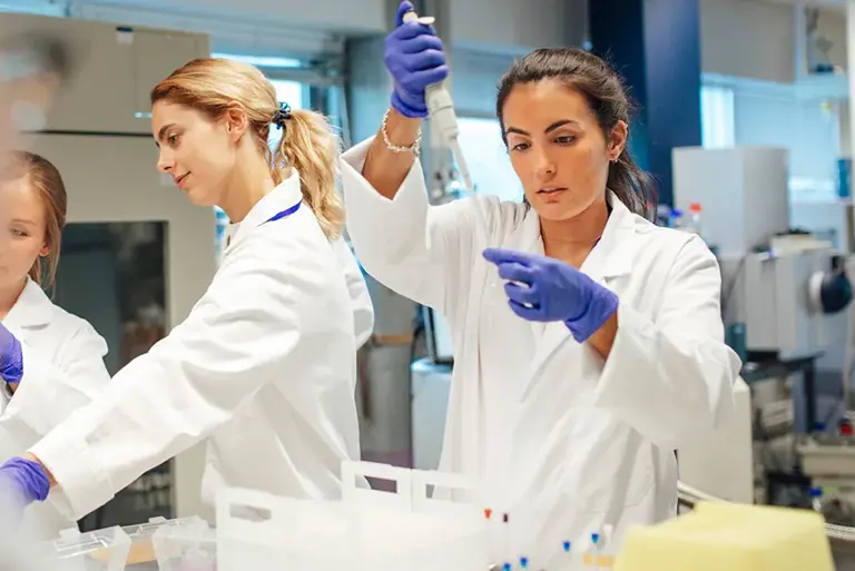 Three young scientists are seen working on a number of vials in the lab