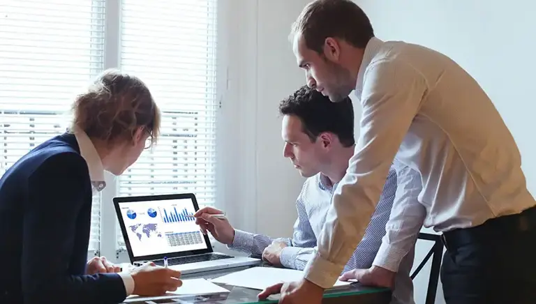 Three analysts look at the charts on a screen