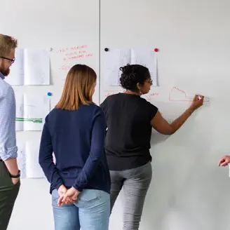 Four office workers drawing on sheets stuck on the wall 