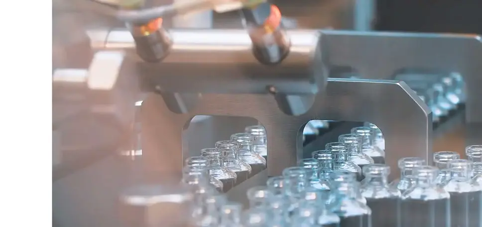 Pharmaceutical production line, crammed with empty glass vials running through a stainless steel machine  