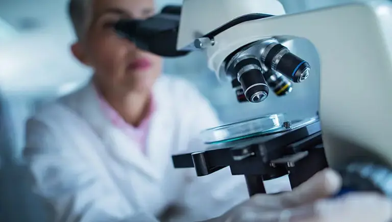 Female scientist looking through microscope