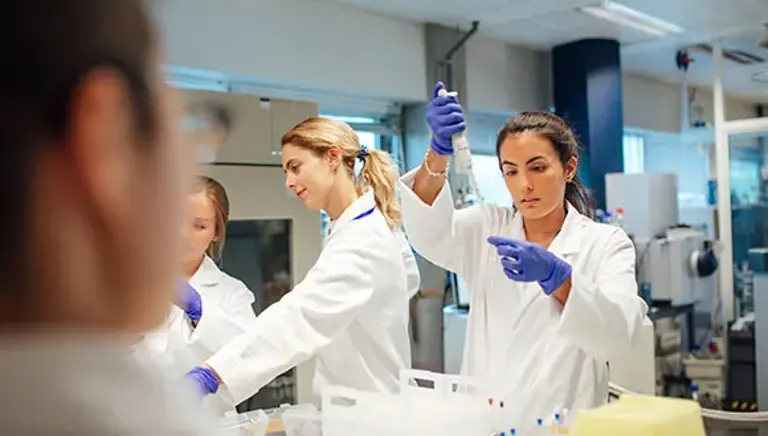 Three young scientists are seen working on a number of vials in the lab