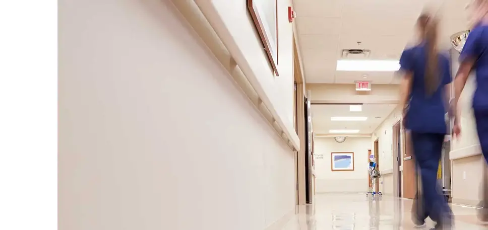 Two nurses, seen from behind, as they walk down a hospital corridor