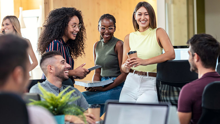 A mixed group of young people smiling and working in an office setting