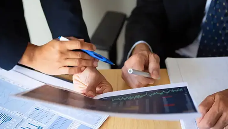 Close up of the hands of two office workers holding print outs of charts