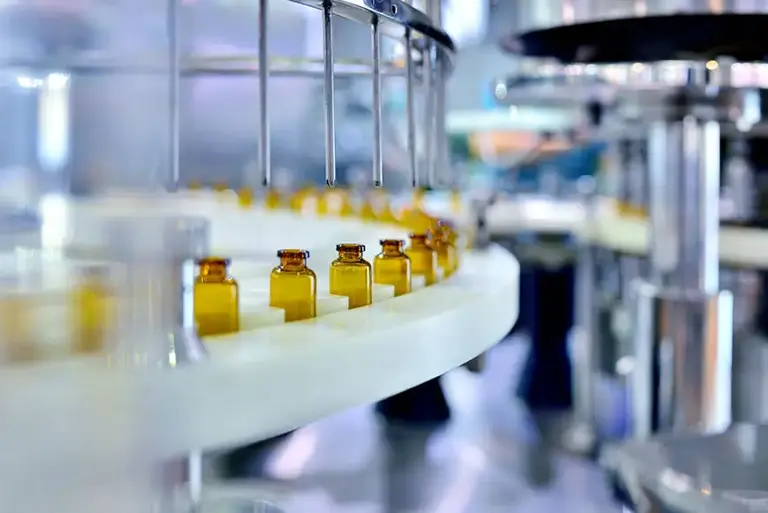 Close up of brown glass medicine bottles about to be filled while running on a factory production line