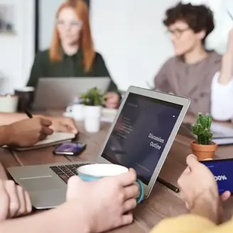 Team of office workers sat around a large conference table having a meeting